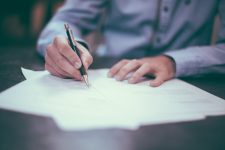 man writing on life insurance contract